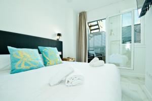 a white bed with two towels on top of it at NineSuites in Seville