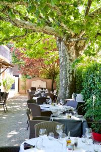 a restaurant with tables and chairs under a tree at Le Bernon in Connaux