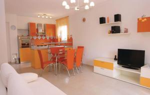 ein Wohnzimmer mit einem Tisch und eine Küche mit orangefarbenen Stühlen in der Unterkunft Apartment Ketica 1041 in Fažana