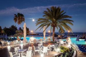 einen Pool mit Tischen, Stühlen und einer Palme in der Unterkunft Grand Teguise Playa in Costa Teguise