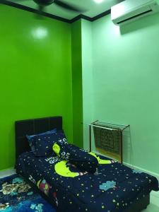 - une chambre dotée d'un lit avec un mur vert dans l'établissement Safwa Homestay Bagan Serai, à Bagan Serai