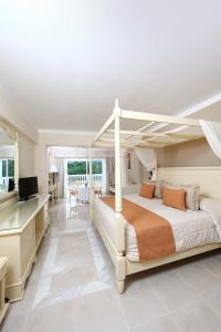 a bedroom with a canopy bed and a dining room at Bahia Principe Grand Aquamarine - Adults Only All Inclusive in Punta Cana