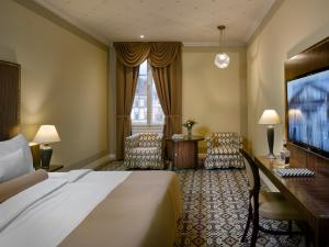 um quarto de hotel com uma cama, uma escrivaninha e cadeiras em Grandezza Hotel Luxury Palace em Brno