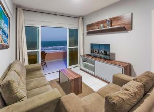 a living room with a couch and a television at Dream Away Uruaú Beach Residences in Uruau