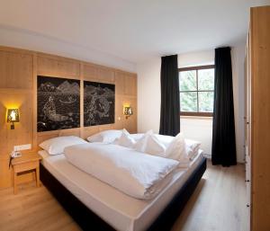 a large white bed in a bedroom with a window at Zin Senfter Residence in San Candido