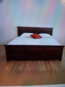 a bed with a red pillow on top of it at Lavendra Guset House in Adams Peak