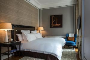
a hotel room with a bed, chair, and nightstand at Hotel de Crillon in Paris
