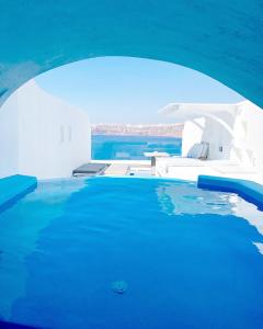 a swimming pool with blue water and white buildings at Astarte Suites in Akrotiri