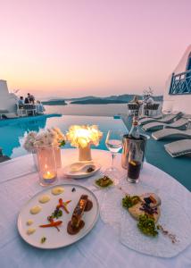 a table with plates of food and a bottle of wine at Astarte Suites in Akrotiri