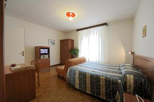 ポッレッタ・テルメにあるHotel Bertusiのベッド、椅子、テレビが備わるホテルルームです。