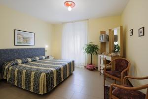 ポッレッタ・テルメにあるHotel Bertusiのベッドルーム1室(ベッド1台、テーブル、椅子付)