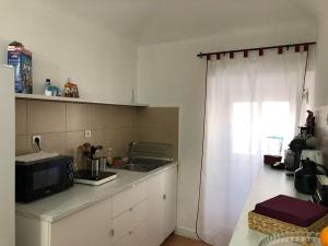 a kitchen with a sink and a microwave and a window at Avis Guesthouse in Évora