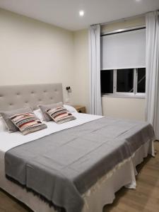 Un dormitorio con una cama blanca con almohadas y una ventana en A Torre do Lago, en Valdoviño