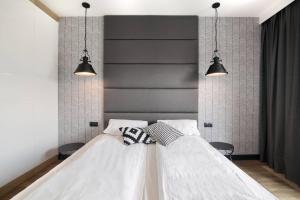 a bedroom with a white bed with two pendant lights at Montevideo Centrum 15 by Grand Apartments in Sopot