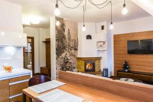 a living room with a fireplace and a table and a tv at udanypobyt Apartamenty Kominkowe in Zakopane