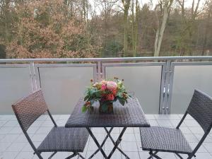 einen Tisch mit einer Blumenvase auf dem Balkon in der Unterkunft Apartment mit Blick auf das Eversten Holz 42qm in Oldenburg