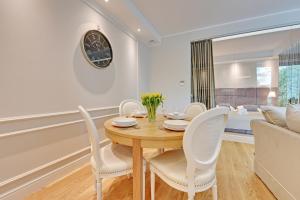 uma sala de jantar com uma mesa de madeira e cadeiras brancas em Montevideo Centrum 4 by Grand Apartments em Sopot