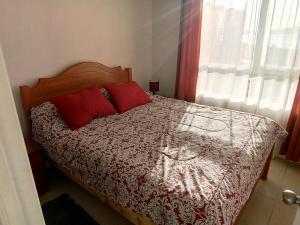 Un dormitorio con una cama con almohadas rojas y una ventana en Muy buena vista y ubicación, en Coquimbo