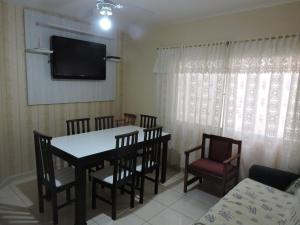 a dining room with a table and chairs and a television at Apto 2 quartos no centro de Bombinhas, 130 metros praia in Bombinhas
