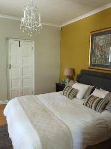 a bedroom with a white bed with pillows and a chandelier at Almond Cottage Bed & Breakfast in Somerset West