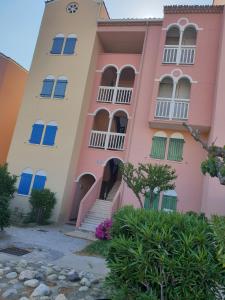 un edificio rosa con ventanas azules y escaleras en Studio cabine au barcares en Le Barcarès