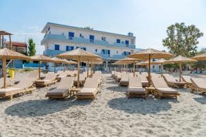 Hotel Kamelo في Vári: مجموعة من الكراسي والمظلات على الشاطئ