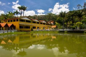 een geel gebouw naast een grote hoeveelheid water bij Pousada carvalho in Conselheiro Lafaiete