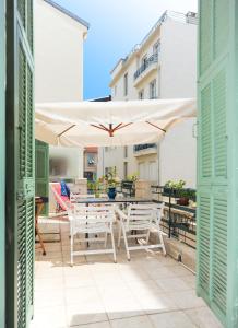 een patio met een tafel en stoelen en een parasol bij La terrasse Apartment Five stars holiday house in Nice