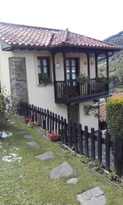 a small house with a balcony and a fence at La casina de santulaya in Cangas del Narcea