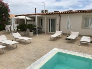 a patio with a pool and chairs and umbrellas at Archiammare Sea in San Lorenzo