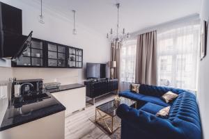 salon z niebieską kanapą i kuchnią w obiekcie Glam Apartments w Toruniu