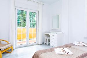 a bedroom with two beds and a desk and a window at AT Almoraide Rooms Suites in Nerja