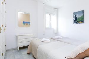 a white bedroom with two beds and a dresser at AT Almoraide Rooms Suites in Nerja