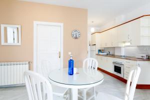 a white kitchen with a table and white chairs at AT Almoraide Rooms Suites in Nerja