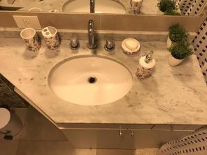 a bathroom sink with a white counter top with cups at Amplio, moderno y luminoso departamento en la mejor zona de Tigre in Tigre