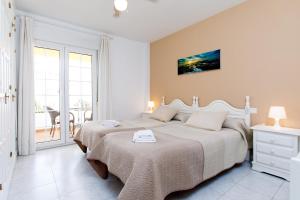 a white bedroom with two beds and a balcony at AT Almoraide Rooms Suites in Nerja