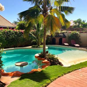a swimming pool with a palm tree in a yard at Villa Les CoCotiers in Saly Portudal