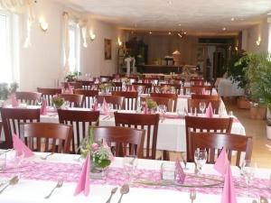 a dining room with tables and chairs with pink bows at Landgasthaus Bonn in Baunatal