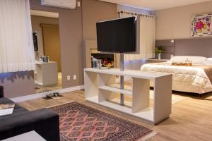 a living room with a television on a white table at Hotel Canto Verde in Gramado