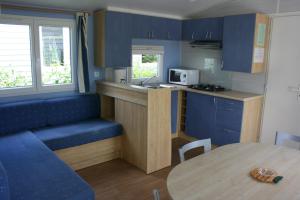 una pequeña cocina con armarios azules y una mesa en Camping Le Walric, en Saint-Valery-sur-Somme