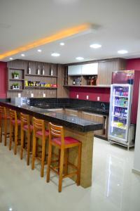 cocina con barra con taburetes de madera y nevera en Evidence Hotel, en Sapucaia