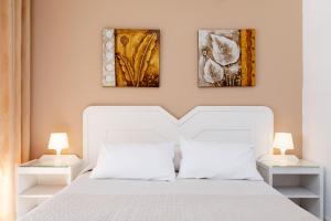a bedroom with a white bed and two paintings on the wall at AT Almoraide Rooms Suites in Nerja
