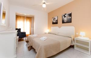 a white bedroom with a bed and a chair at AT Almoraide Rooms Suites in Nerja