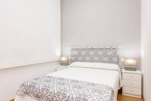 a white bedroom with a bed and two night stands at Canadian 1 in Córdoba