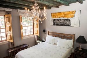 a bedroom with a bed and a chandelier at Pousada Do Largo in Tiradentes