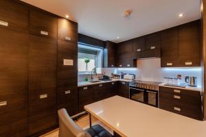 a kitchen with wooden cabinets and a white table at The Town House Kinsale, Hosted by Exquisite holiday homes, sleeps 16 in Kinsale