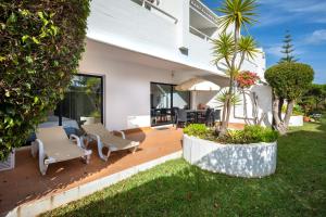 a house with a wooden deck with chairs and trees at Victory Village 3A in Quinta do Lago