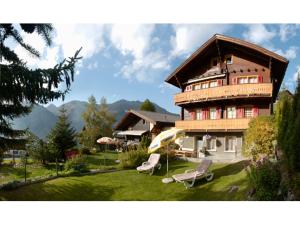 a large house with two chairs and an umbrella at Chalet Heimetli in Grächen