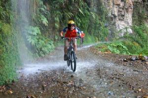 a man riding a bike down a dirt road at Camping e Pousada Paiol in Águas da Prata