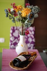 een vaas met bloemen en een fles wijn op een tafel bij Apartments Pri Adamsovih in Čatež ob Savi